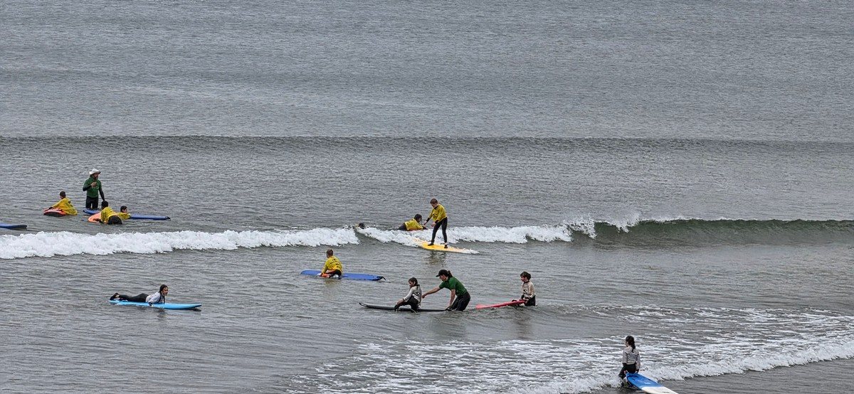 junior beginner surfers catching waves